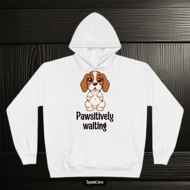 Funny hoodie illustrating a spaniel sitting upright with wide, excited eyes and its paws clasped expectantly.