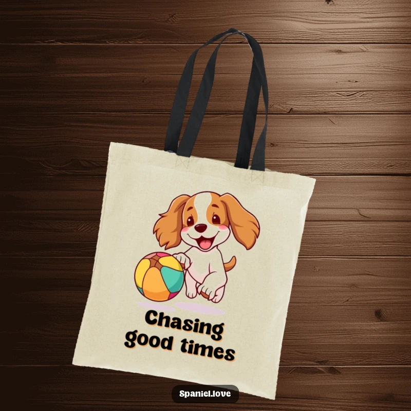 Funny tote bag depicting a spaniel dog mid-chase, ears flapping, joyfully pursuing a colorful, bouncing ball, embodying pure canine happiness.