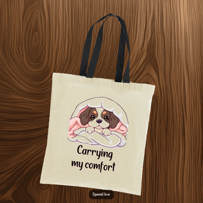 Funny tote bag showcasing a spaniel puppy peeking from soft blankets, perfect for carrying charm and essentials.